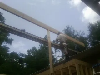 Carpenter setting a ridge beam over a new addition frame — Ice Dam Removal by Roofing Brothers in Yulee