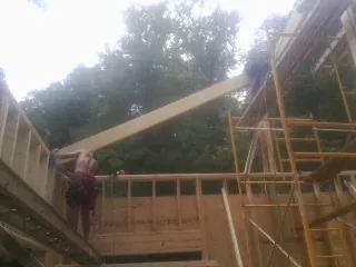 Carpenter raising a rafter beam on a new second story frame in Yulee