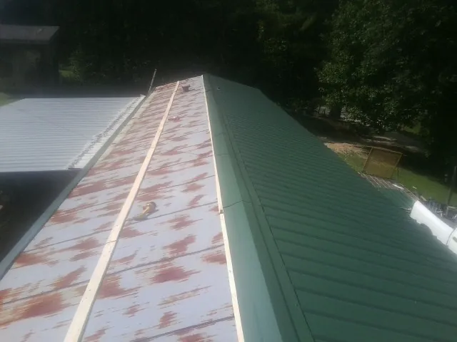 Old rusted panels beside newly installed green metal roofing — Wind Damage Roof Repair by Roofing Brothers in Yulee