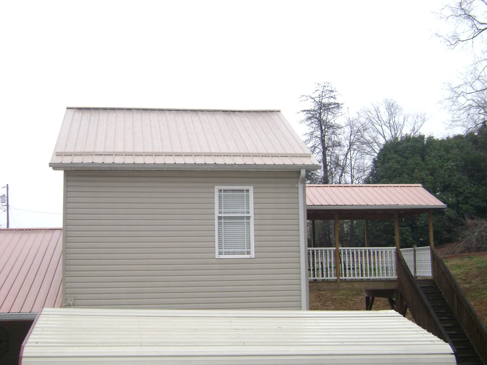 Tan metal roofs on a two story addition and attached porch, from a Roof Replacement job in Yulee